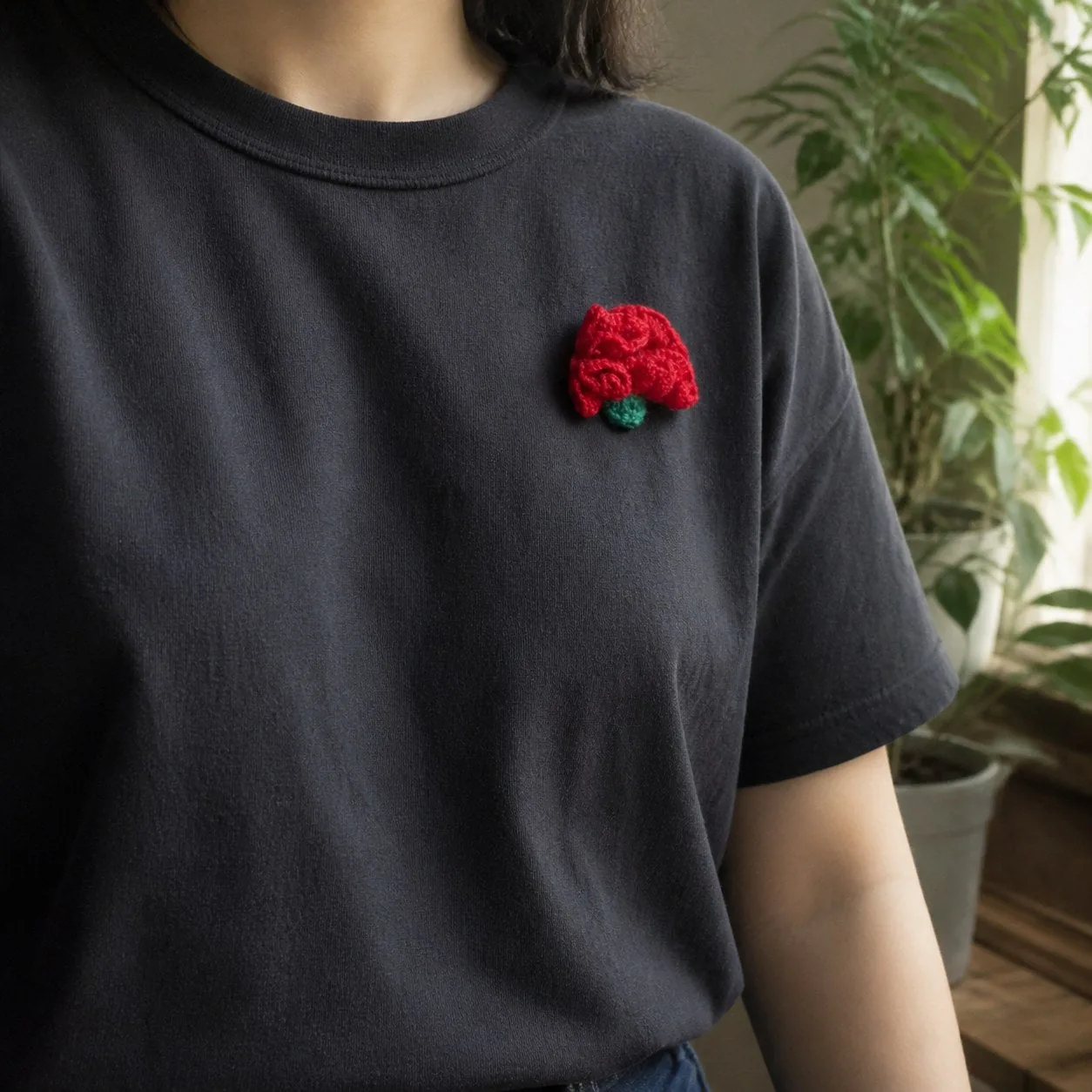 Cravo de lã vermelho pregado numa t-shirt escura, ao peito