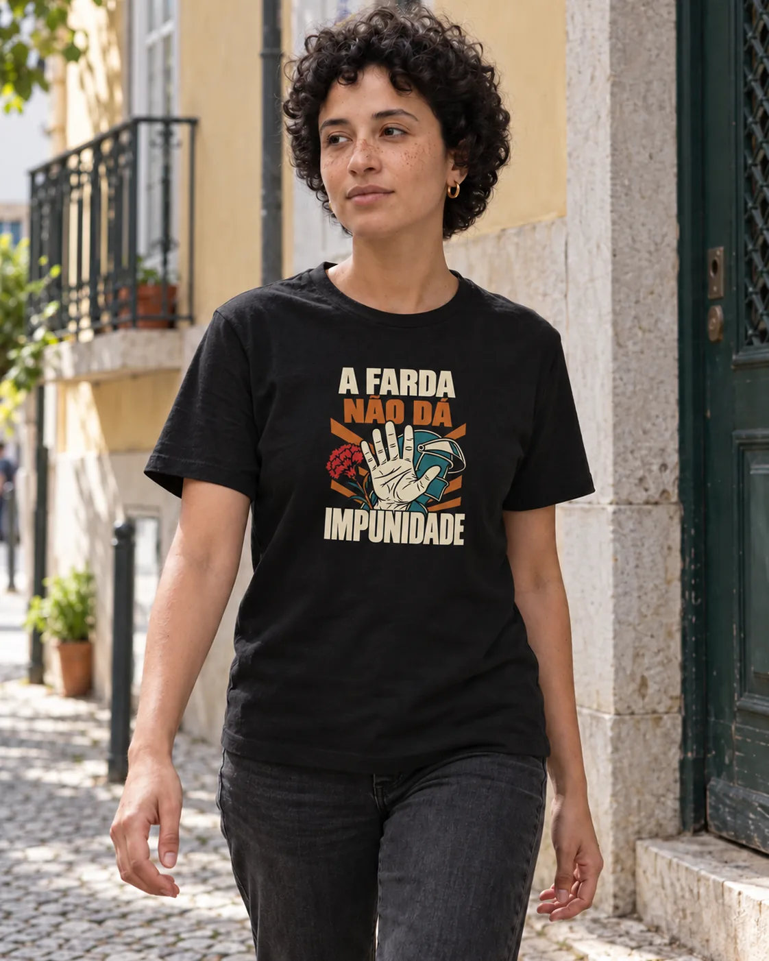 Pessoa a vestir a T-shirt A Farda Não Dá Impunidade em preto, numa rua de Lisboa ao sol