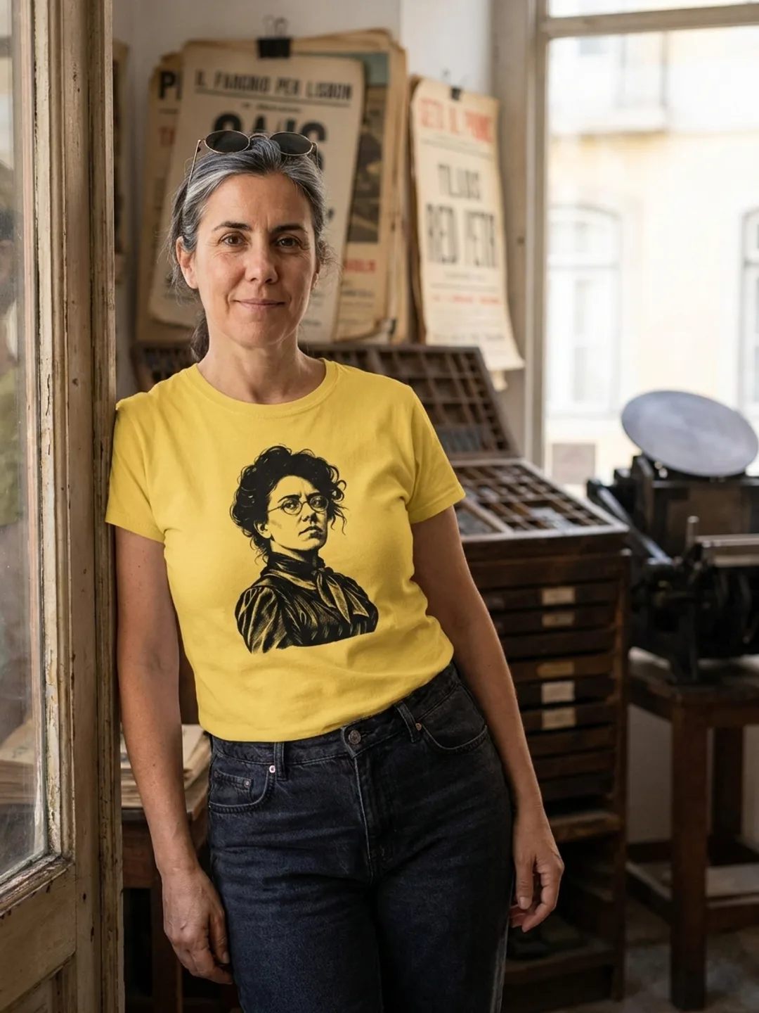 Pessoa a vestir a T-shirt Emma Goldman em amarelo, à porta de uma tipografia antiga