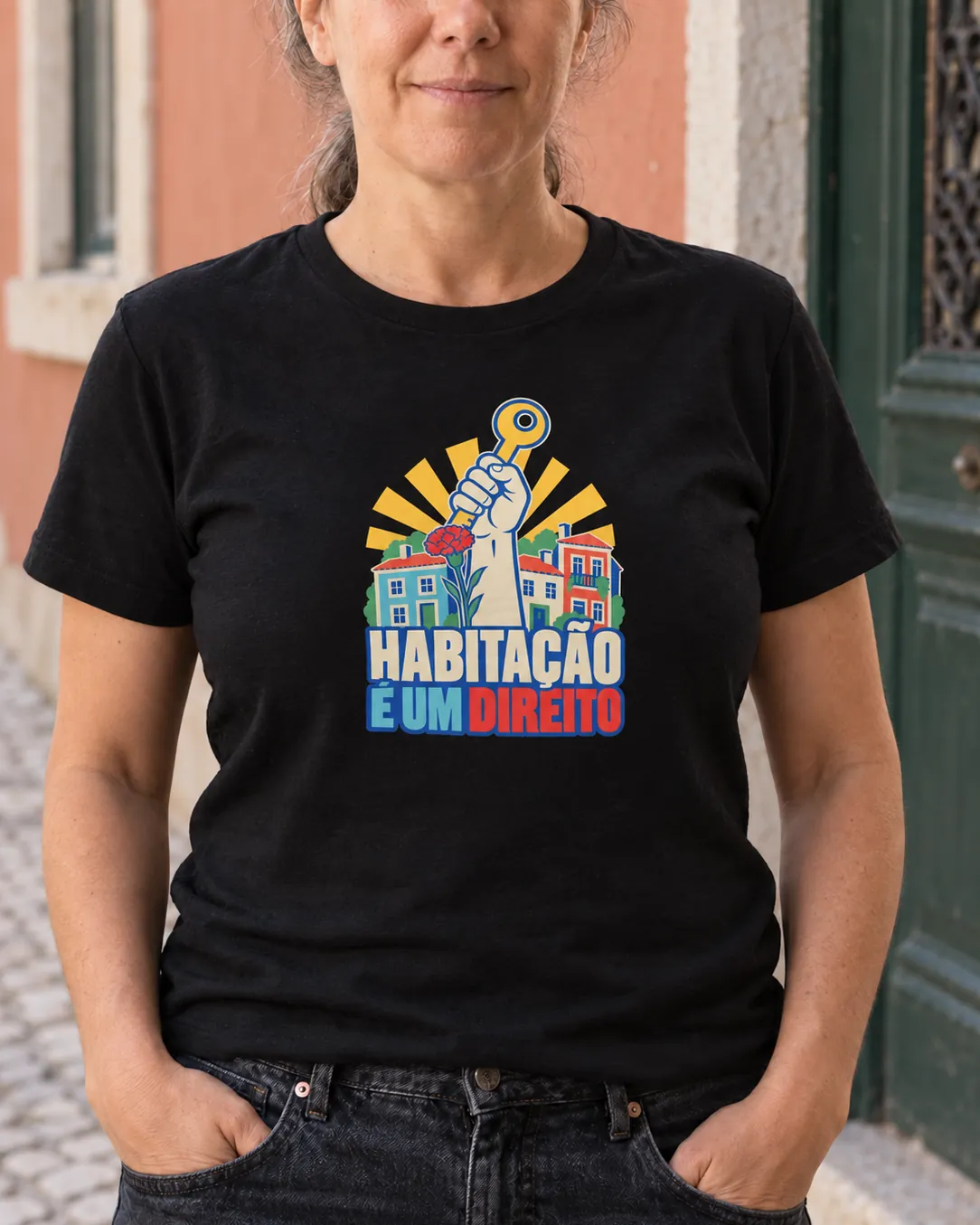 Pessoa a vestir a T-shirt Habitação É Um Direito em preto, numa rua de Lisboa de dia