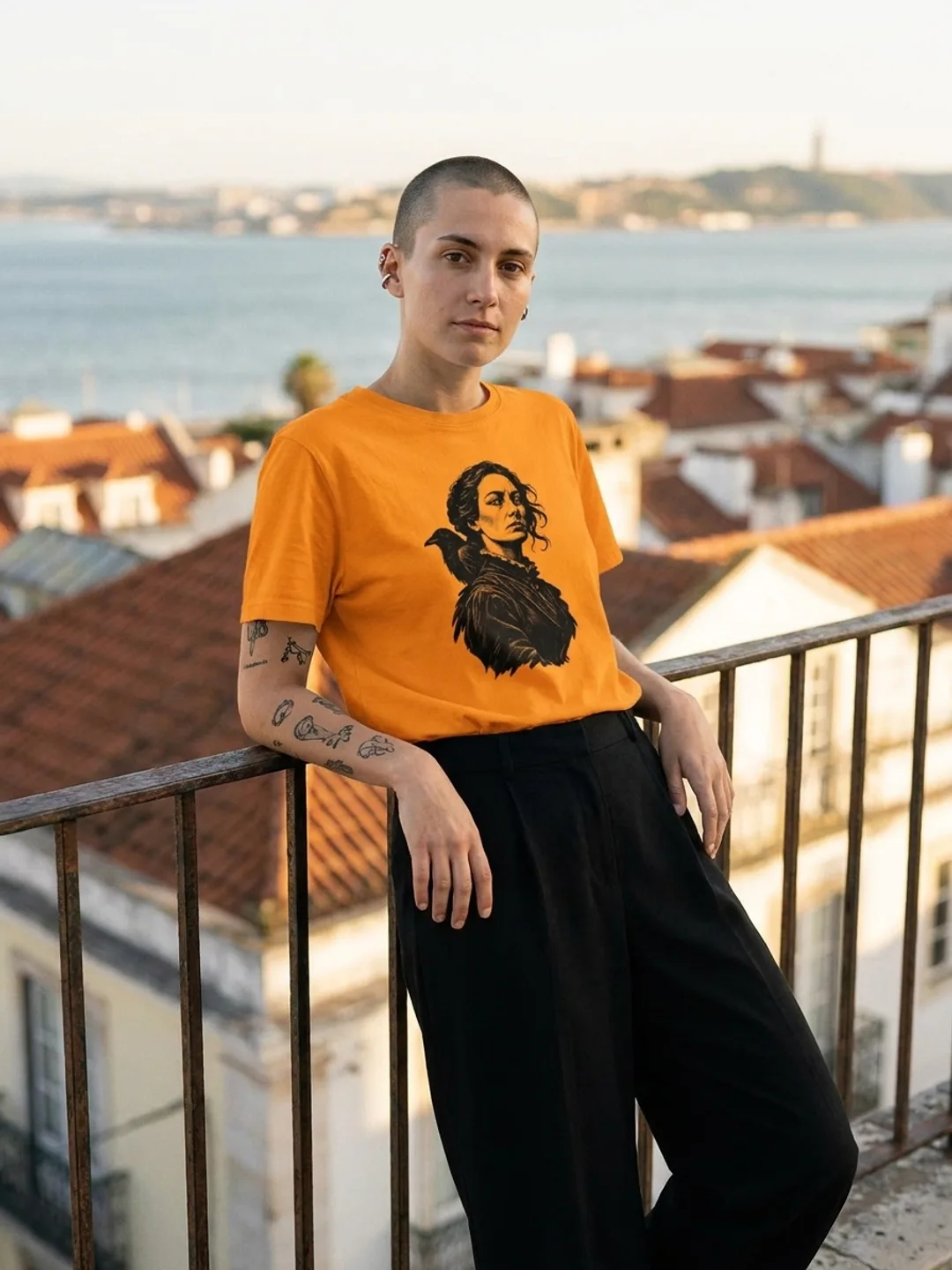 Pessoa a vestir a T-shirt Louise Michel em laranja, num miradouro de Lisboa
