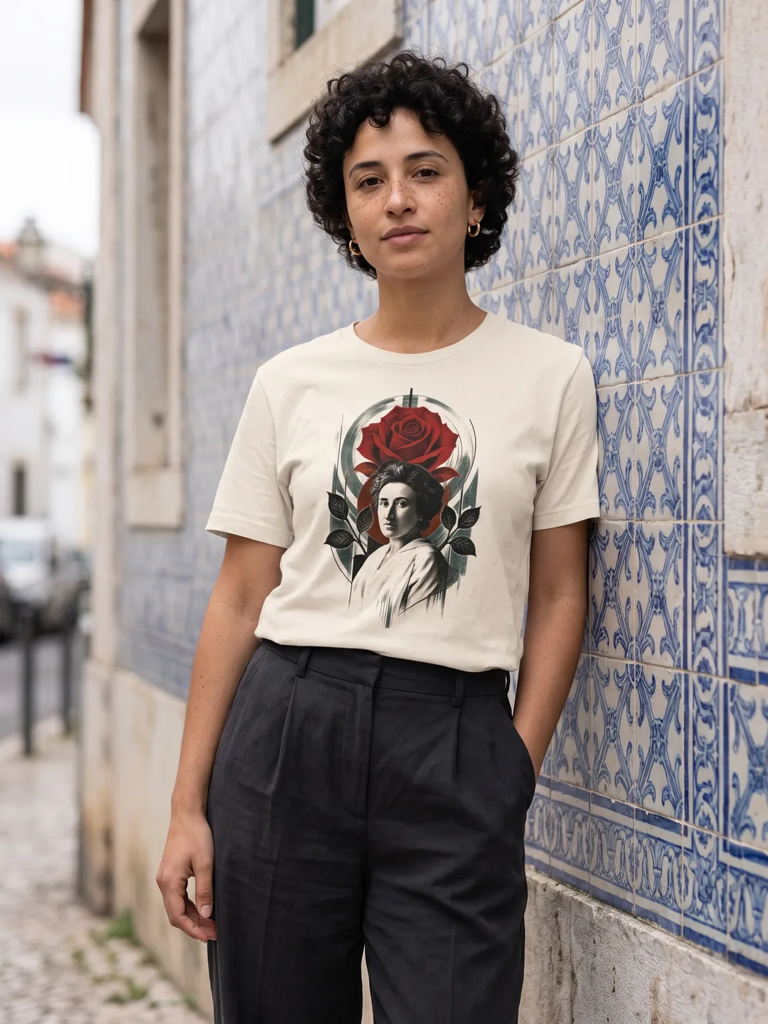 Pessoa a vestir a T-shirt Rosa Luxemburgo em natural, encostada a uma parede de azulejos